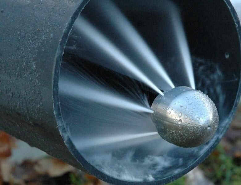 Гидродинамическая насадка очищает внутреннюю поверхность канализационной трубы струями воды